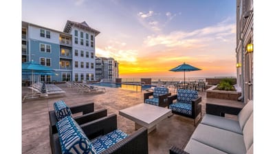 Outdoor pool area with seating and umbrellas at sunset