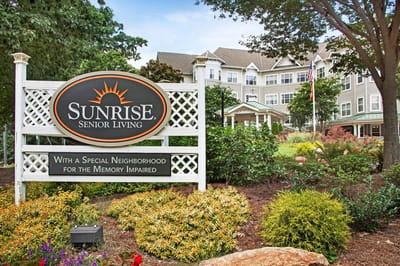 Exterior view of Sunrise Senior Living facility sign and gardens