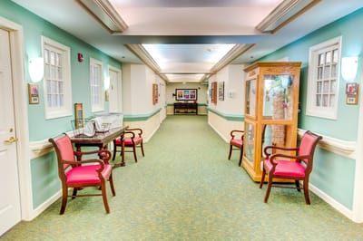 A hallway with seating and display case in a senior living facility.