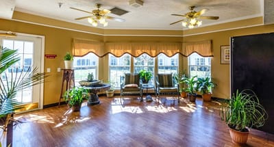 Common area with seating and plants near large windows