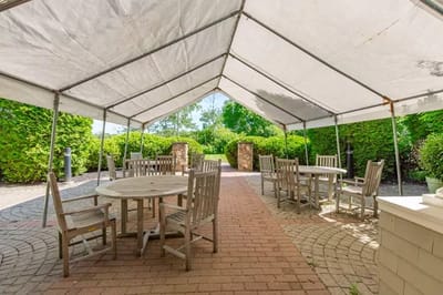 Outdoor seating area under a tent surrounded by greenery