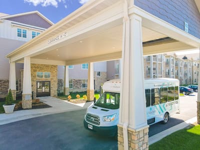 Entrance of a senior living facility with a shuttle bus