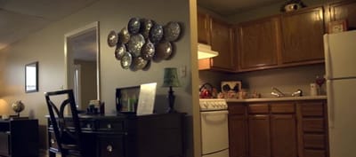 A cozy apartment interior with a desk and kitchen area