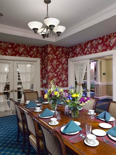 Dining room setup with floral wallpaper and a large dining table