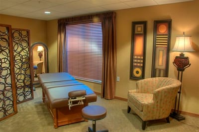 A massage therapy room with a massage table and decor