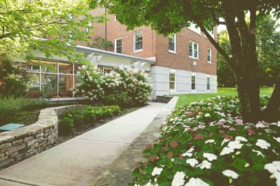 Exterior view of a facility entrance with flowers and paths