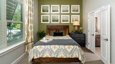 A well-decorated private resident room with a bed and artwork
