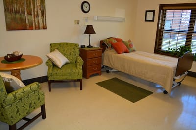 Cozy resident room with bed, chairs, and a small table