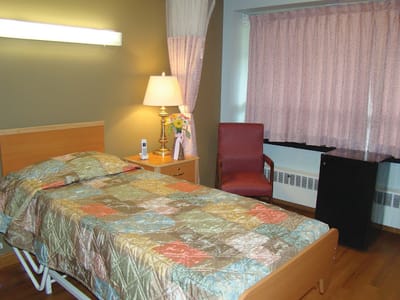 A private resident room with a bed and chair