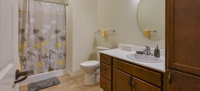 A well-lit bathroom with a shower curtain, sink, and toilet.