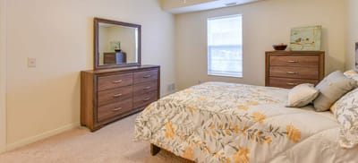 A well-furnished bedroom with a floral bedspread and wooden furniture.