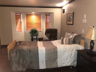 A cozy private resident room with a bed and chair