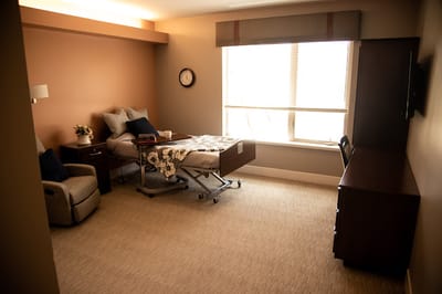 Interior of a private resident room with a bed and chair