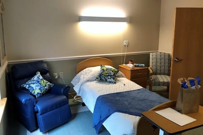 A cozy resident room with a bed and chair