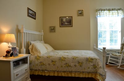 A cozy resident room with floral bedding and natural light