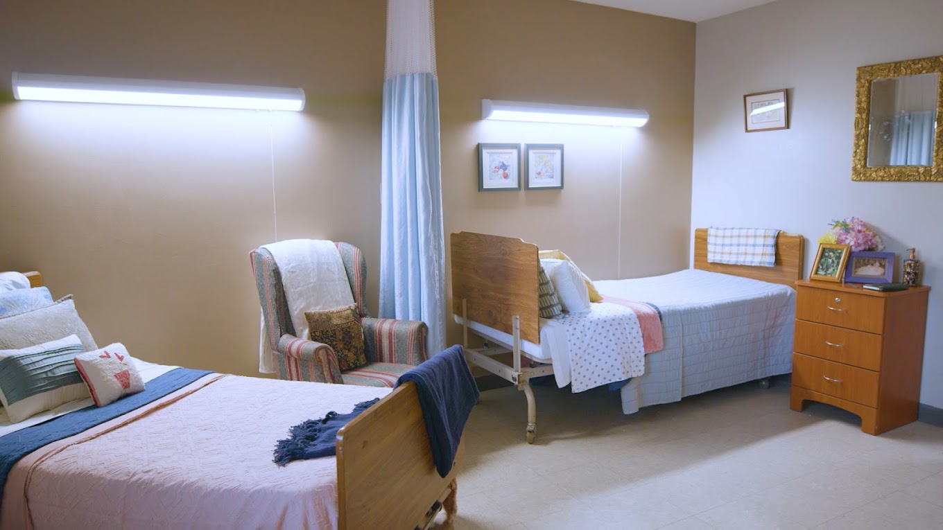 A cozy resident room with two beds and armchair