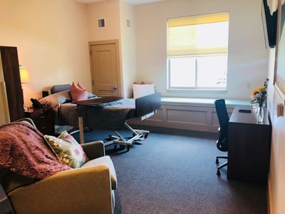 A private resident room with a bed and seating area