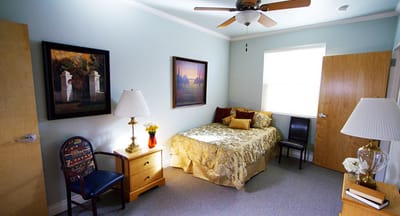 Brightly decorated resident room with bed and fan
