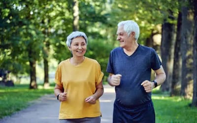 Two seniors jogging together in a park