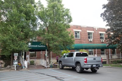 Exterior view of Maplewood Gardens with residents and vehicle