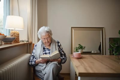 Elderly woman reading a book in a bright room