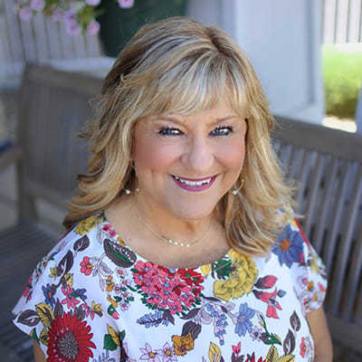 A smiling woman in a floral top outdoors