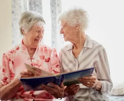 Two residents sharing a book in a cozy room