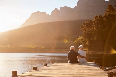 Couple sitting on a dock overlooking a lake at sunset