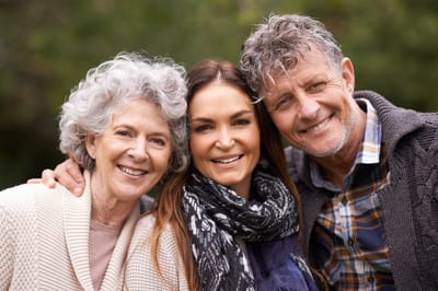 Three smiling individuals posing outdoors