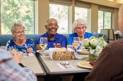 Residents enjoying a meal and conversation in the dining room