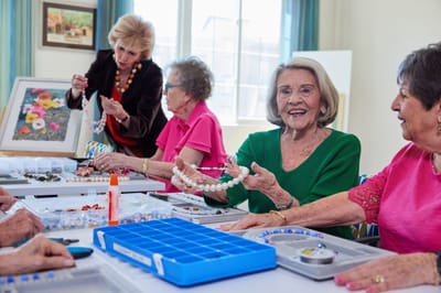 Residents creating jewelry in a bright activity room