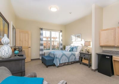 Brightly decorated private resident room with a bed and seating