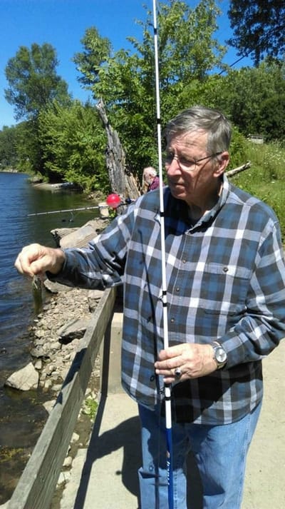 A man fishing near a lakeside in sunny weather
