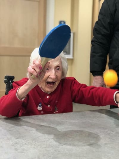 Resident playing table tennis in a lively common area