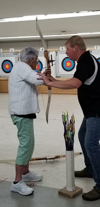Residents participating in an archery activity indoors