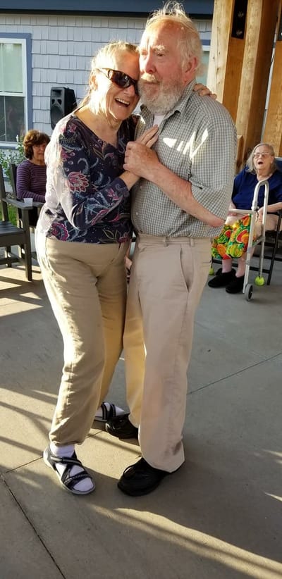 Couple dancing joyfully outdoors at a senior living facility