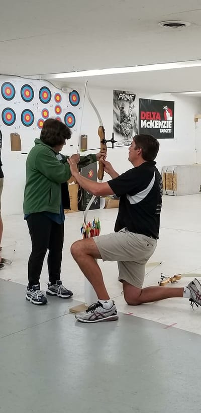 Residents participating in an archery activity indoors