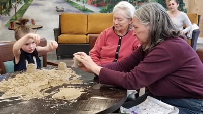 Residents and a child engaged in sand play activity