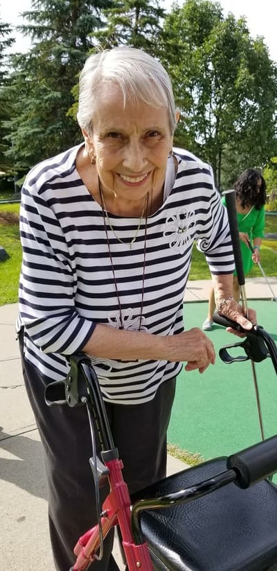 Older woman smiling with a walker outdoors