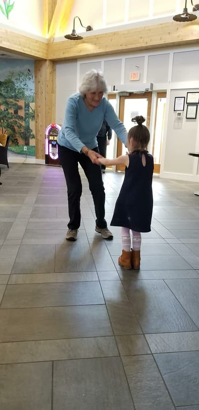A resident dancing with a child in a common area