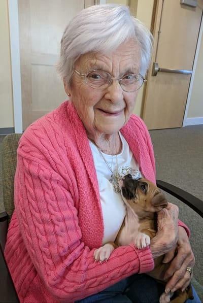 A cheerful resident holding a puppy in an indoor setting