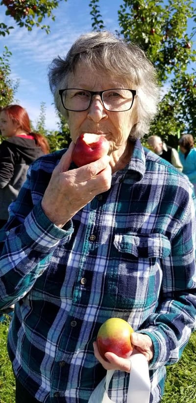 Resident enjoying apples in an orchard at an outing