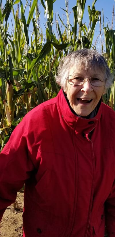 Resident in a cornfield, smiling in a red jacket