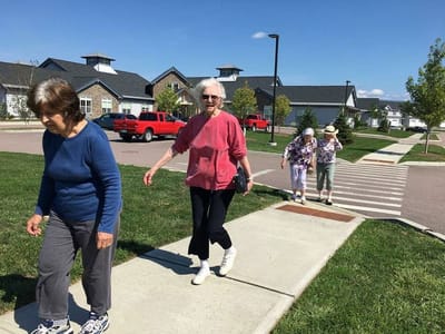 Residents walking along a path in a sunny outdoor area