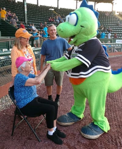 An elderly resident interacting with a mascot at an outdoor event