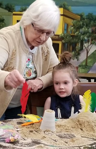 An elderly woman assisting a young girl with craft activities