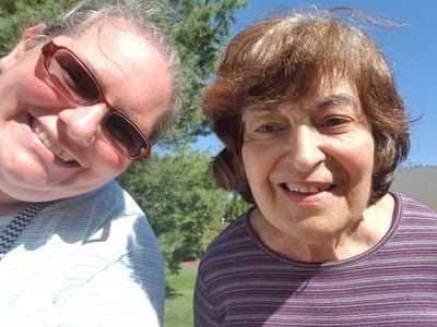 Two residents smiling outdoors in sunlight