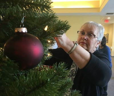 Resident decorating a Christmas tree in the common area