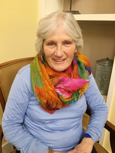 Smiling elderly woman in colorful scarf seated indoors