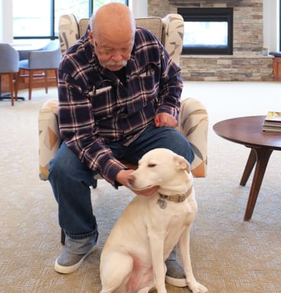 Resident petting a dog in a cozy common area